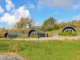 Three cabins with large windows and a gravel path at Lodge 2 near Pontyates