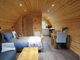 A living area with a bed, sofa, table, and kitchen at Lodge 3 Pontyates