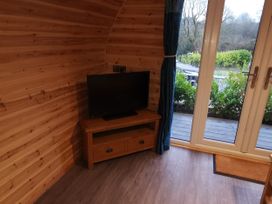 A living room with a television and door at Lodge 3 in Pontyates