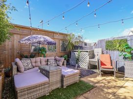 A garden with outdoor sofa, umbrella, plants, and decking at 21 Olympic Way Plymouth