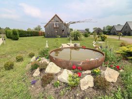 A pond surrounded by flowers and rocks with a house in the background at James Ville Marina Lodge 10 Brigg