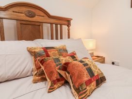 A bed with decorative pillows and a lamp on a bedside table at Lane End in North Molton