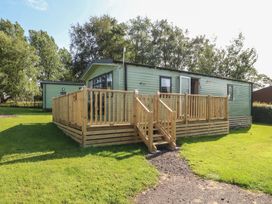 A cabin with a wooden deck and steps at Barnes Retreat in Carnforth