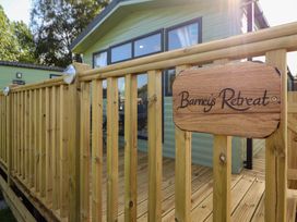 A deck with a wooden railing and a sign at Barneys Retreat in Carnforth