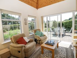 A conservatory with seating area and sliding doors leading to patio at Knockroe Lodge