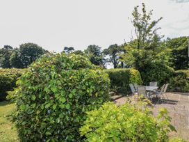 A garden with a table and chairs on a stone patio at Knockroe Lodge 