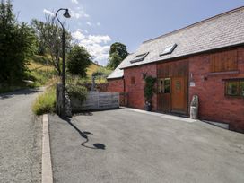 An outdoor area with a red brick building and a gravel path at Woodpecker Cottage in Llangollen