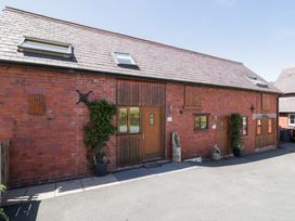 An exterior view of a cottage with brick wall and wooden door at Woodpecker Cottage in Llangollen
