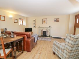 A living room with a sofa, armchair, and fireplace at Woodpecker Cottage in Llangollen