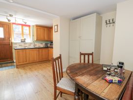 A kitchen with wooden cabinets and a table at Woodpecker Cottage in Llangollen