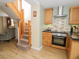 A kitchen with cabinets and stairs at Woodpecker Cottage in Llangollen