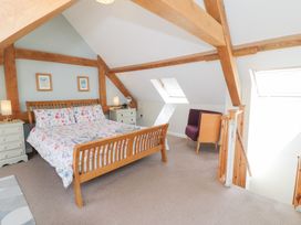 A bedroom with a bed and chair at Woodpecker Cottage in Llangollen
