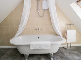 A bathroom with a bathtub and towel rail at Woodpecker Cottage Llangollen