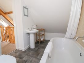 A bathroom with a bathtub and washbasin at Woodpecker Cottage in Llangollen