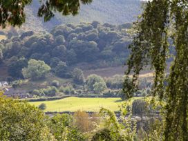A view of trees and grass with houses at Woodpecker Cottage in Llangollen