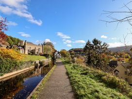 A pathway alongside a canal with buildings and trees at Woodpecker Cottage in Llangollen