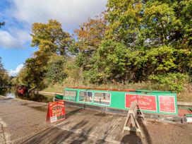A narrowboat docked by the canal with a sign for boat trips at Woodpecker Cottage Llangollen