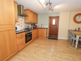 A kitchen with wooden cabinets and appliances at Owl Cottage in Llangollen
