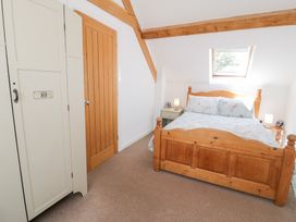 A bedroom with a wood bed and wardrobe at Owl Cottage in Llangollen