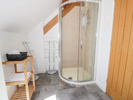 A bathroom with a shower and shelves at Owl Cottage in Llangollen