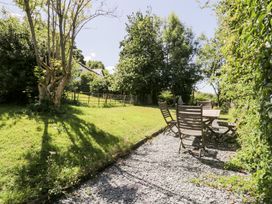 A garden with a table and chairs on a gravel path at Owl Cottage in Llangollen