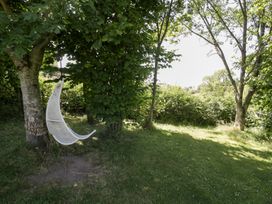 A garden with a hanging white hammock among trees at Owl Cottage in Llangollen