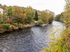 A river bordered by trees and residential buildings at Owl Cottage Llangollen