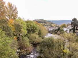 A river flowing through trees and houses at Owl Cottage in Llangollen