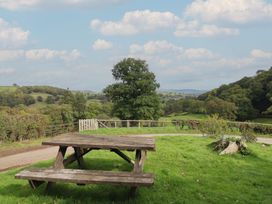 A picnic table on grass with trees and a fence at Upper Pandy Farm in Welshpool