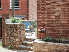 A garden with a stone wall and seating area at Jams in Lympstone