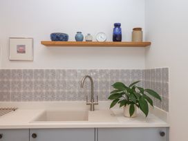 A kitchen with a sink and shelf items at Jams in Lympstone