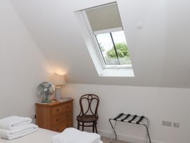 A bedroom with a bed, fan, lamp, and chair at Jams in Lympstone