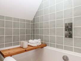 A bathroom with a bathtub and towels on a shelf at Jams in Lympstone