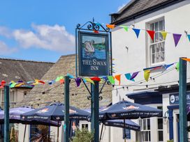An outdoor area with a pub sign and umbrellas at The Swan Inn in Lympstone