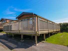 A cabin with a wooden deck in an outdoor area at No 13 Broadfield Farm Holiday Park Saundersfoot