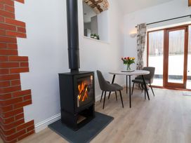 A dining room with a wood stove and table at Hedgehog Highway Parkham