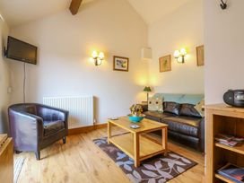 A living room with a sofa, armchair, and television at The Kiln Mendham near Harleston