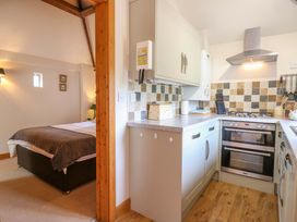 A kitchen with a bed visible in the background at The Kiln Mendham near Harleston