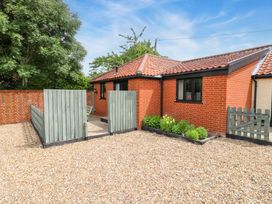 A cottage exterior with a gravel area and wooden fence at The Golden Cross in Mendham near Harleston