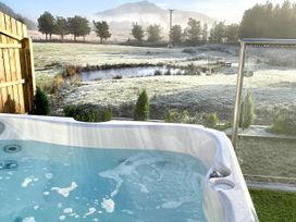 A hot tub with water overlooking a field and mountains at Crofters Suite