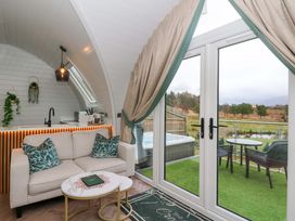 A living room with a sofa and kitchen area at Crofters Suite