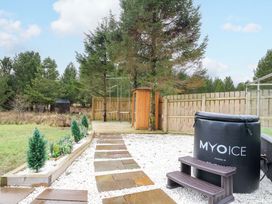 An outdoor area with a spa, tree, and stone path at Crofters Suite
