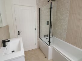 A bathroom with a bathtub, shower, and sink at Ty Landsker in Milford Haven
