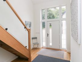 A hallway with a staircase and a chair at Ty Landsker in Houghton near Neyland