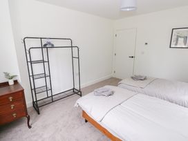 A bedroom with two beds and a clothing rack at Ty Landsker Houghton near Neyland