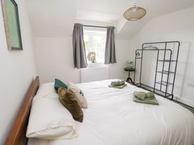 A bedroom with a bed and a clothes rack at Ty Landsker in Houghton near Neyland
