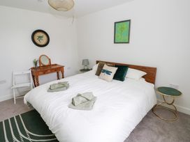 A bedroom with a bed, bedside table, lamp, mirror and chair at Ty Landsker in Houghton near Neyland
