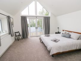 A bedroom with a bed and large windows at Ty Landsker in Houghton near Neyland