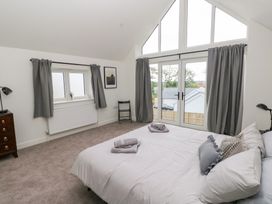 A bedroom with a bed and windows at Ty Landsker in Houghton near Neyland
