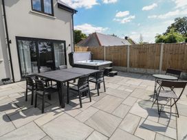 An outdoor area with a table, chairs, and hot tub at Ty Landsker in Houghton near Neyland